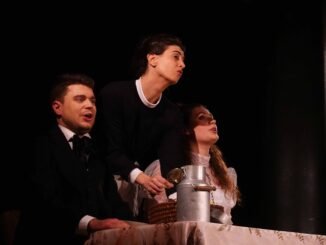 photo de 2 femmes et 1 homme devant une table sur laquelle est posé un pot à lait, le tout sur fond noir