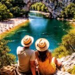 photo d'un couple de dos avec un chapeau de paille assis devant un lac