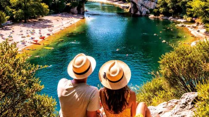 photo d'un couple de dos avec un chapeau de paille assis devant un lac
